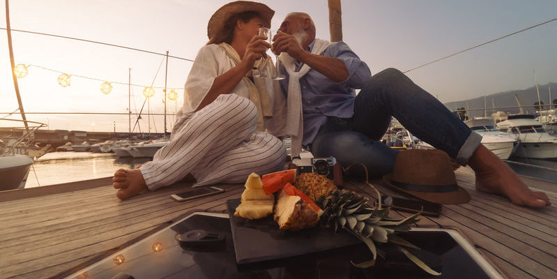 riche Senior couple toasting champagne on sailboat vacation - Happy ma